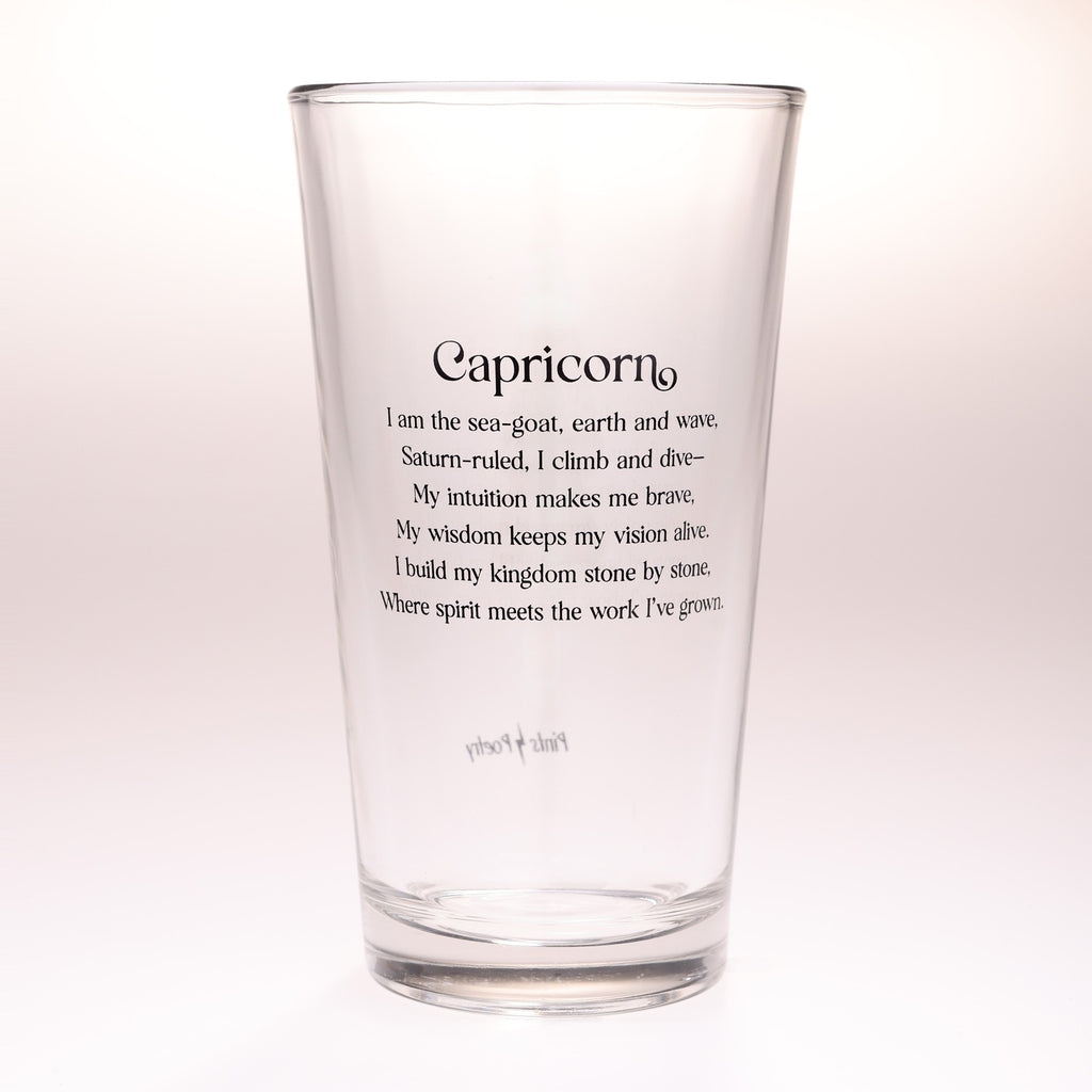 A clear glass drinking tumbler with black printed text reading 'Capricorn' and a poem beneath it, shown on a plain light background.