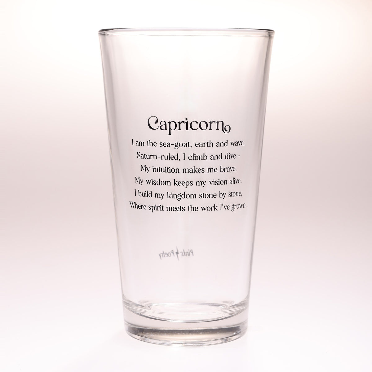 A clear glass drinking tumbler with black printed text reading 'Capricorn' and a poem beneath it, shown on a plain light background.