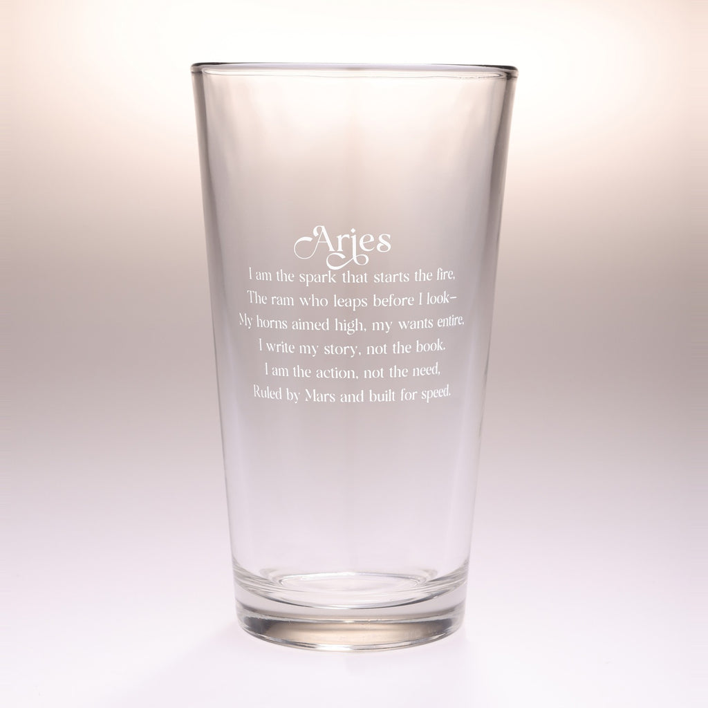 A clear glass pint glass with white printed text reading 'Aries' followed by an astrological quote, shown on a clean white background.