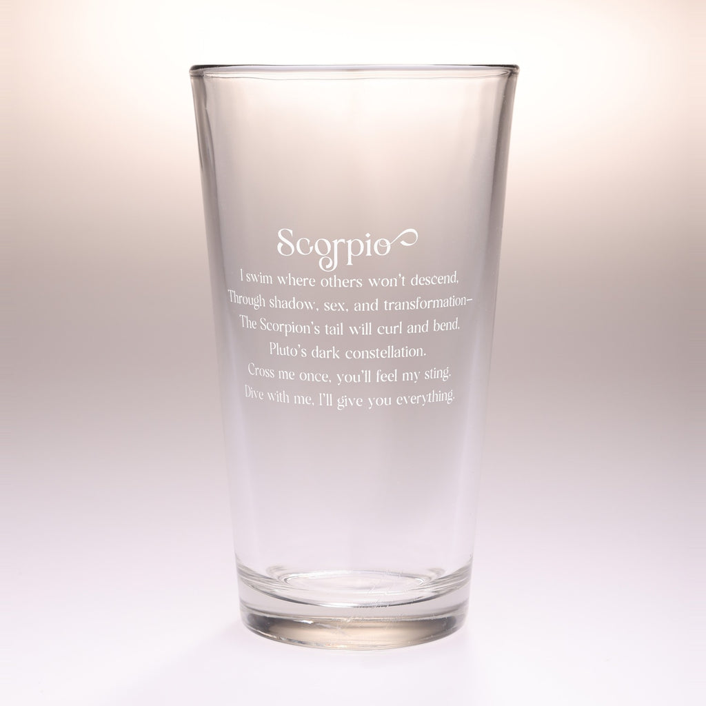 A clear glass pint glass with frosted white text that reads 'Scorpio' and a poem associated with the Scorpio zodiac sign, shown on a neutral light gray background.