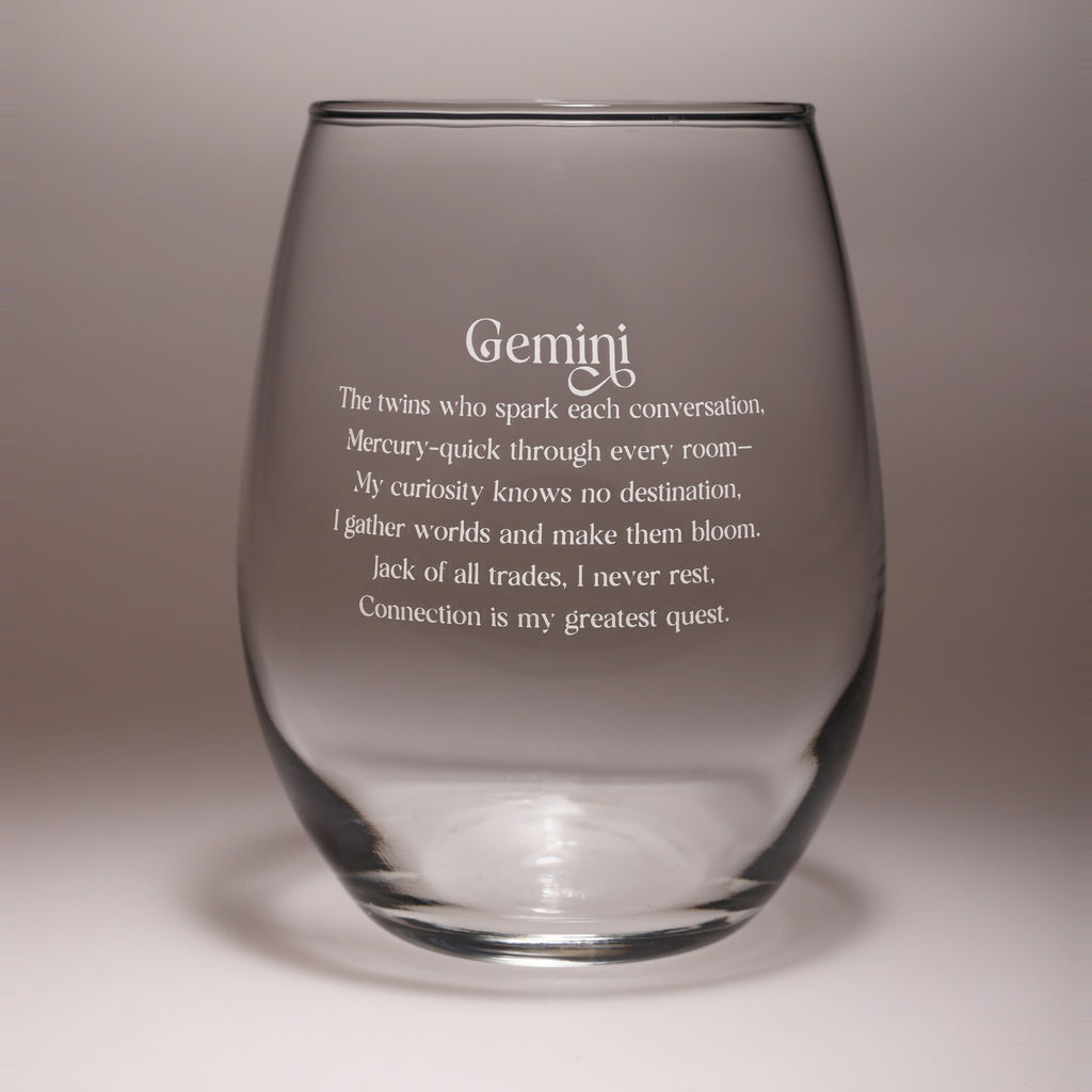 A clear stemless wine glass with white engraved text reading 'Gemini' and a Gemini zodiac quote, shown on a neutral gray background.