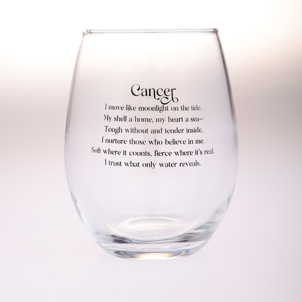 A clear stemless wine glass with black printed text reading 'Cancer' followed by a poem about moonlight, shell, heart, and water, shown on a plain light background.