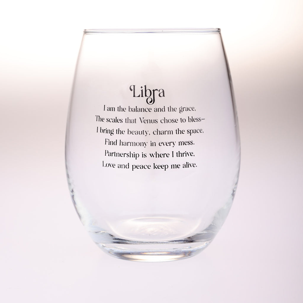A clear stemless wine glass with black printed text reading 'Libra' and a poem about Venus and harmony, shown on a soft white background.