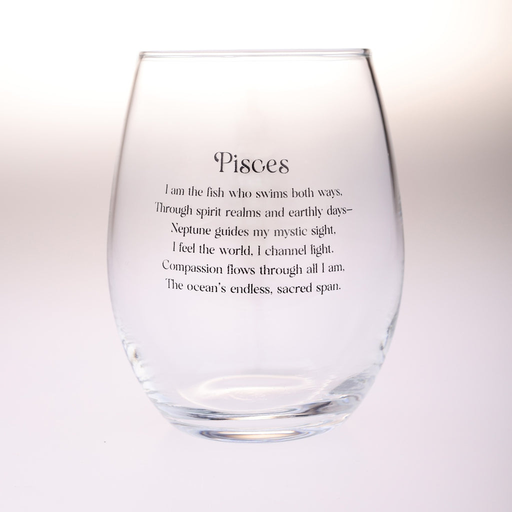A clear stemless wine glass with black printed text reading 'Pisces' followed by a poem about the Pisces zodiac sign, shown on a plain light background.