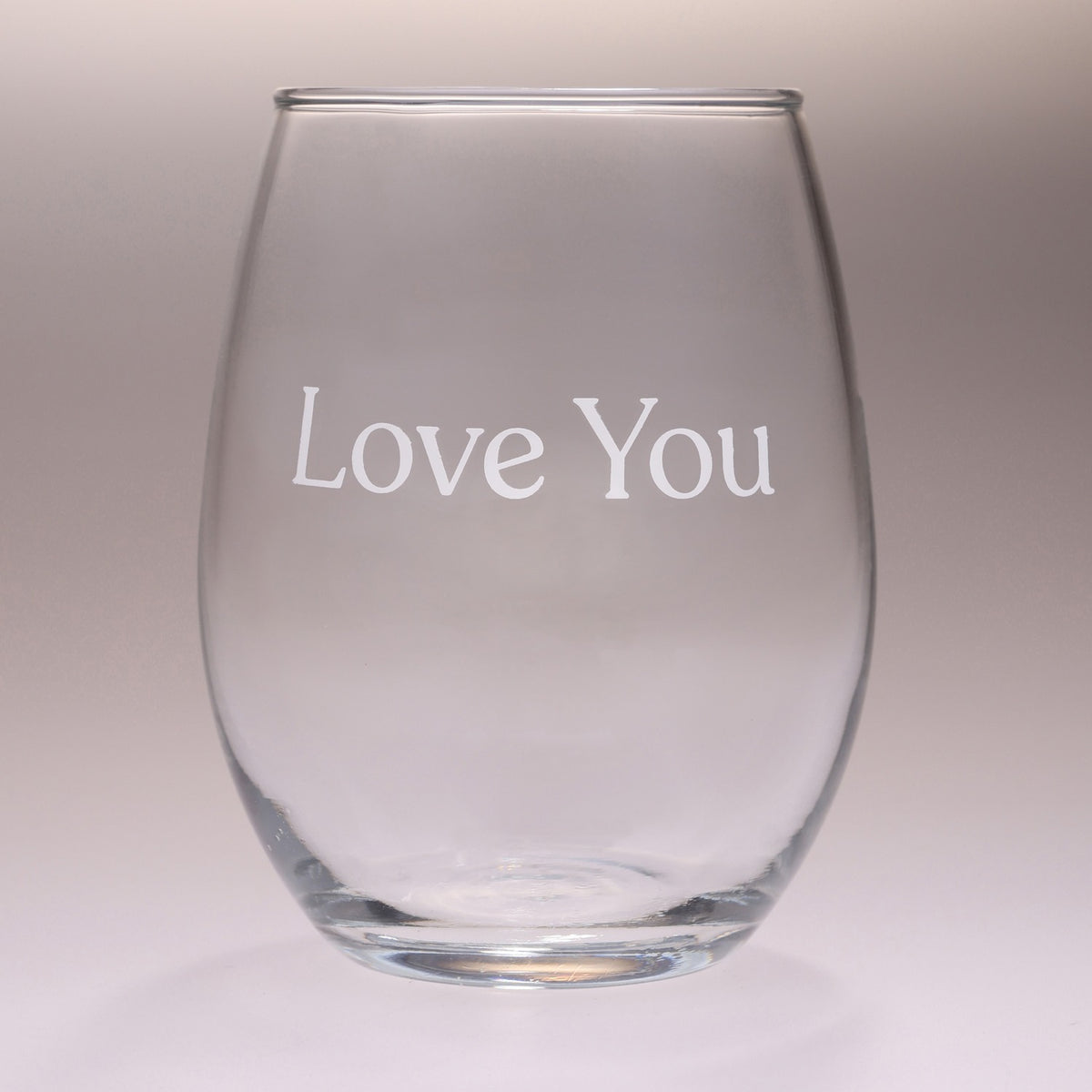 A clear stemless wine glass with the words 'Love You' printed in white serif lettering on the front, set against a neutral light gray background.