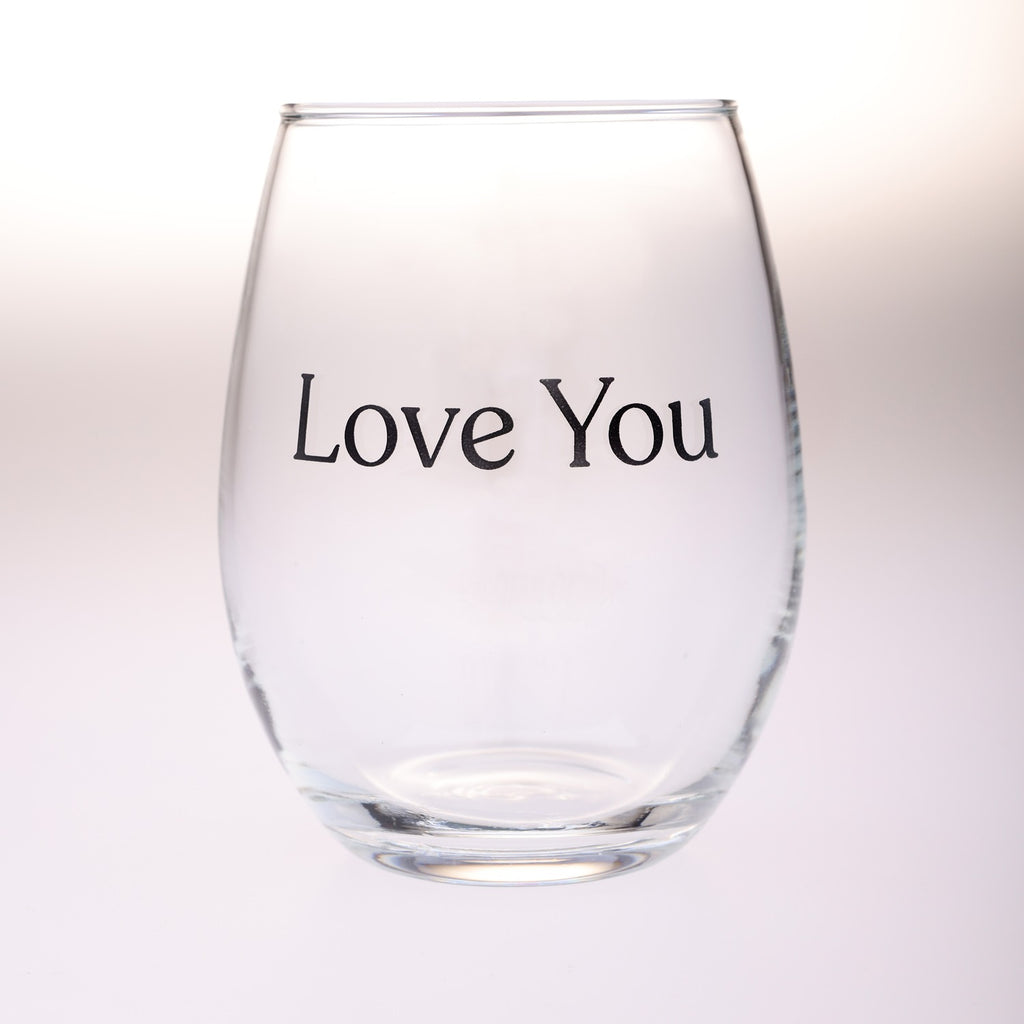 A clear stemless wine glass with the words 'Love You' printed in black serif text on the front, set against a soft white background.